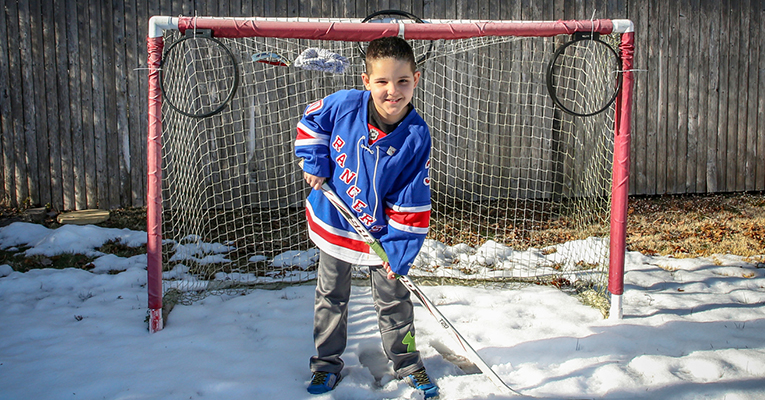Child smiling and posing with hockey gear